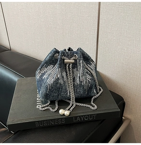 Detail of denim bucket bag showing silver sequins, drawstring, and pearl charms