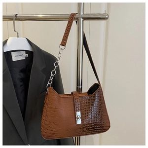Detail of brown crocodile pattern shoulder bag with silver metal twist lock and chain strap