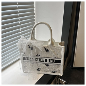 Detail of white tote bag with black rose patterns and a delicate lace bow decoration
