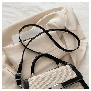 Détail d'un sac à main beige tissé avec bordure en cuir noir et fermoir en métal argenté