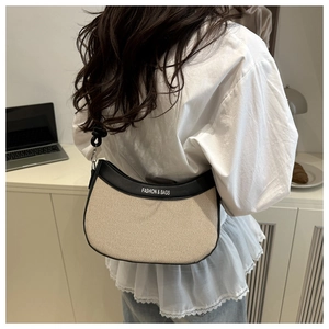 Détail du sac à bandoulière en toile avec bordure noire et décoration de nœud sur le côté