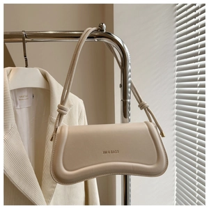 Detail of beige underarm bag with wavy structure and elegant knotted shoulder strap