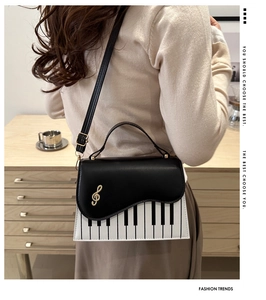 Detail of piano keyboard pattern handbag with golden musical note and leather handle