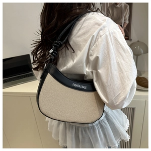 Détail d'un sac demi-lune en toile rétro avec bordure en cuir porté à l'épaule