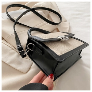Détail de la texture contrastée et du fermoir rotatif argenté sur le sac noir et blanc
