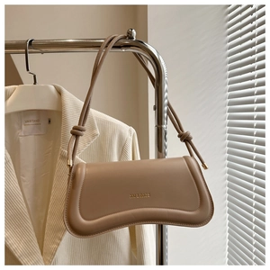 Detail of knot accent on beige faux leather shoulder bag with XM & BAGS logo