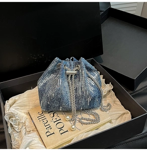 Detail of sequined denim bucket bag with pearl chain straps inside a gift box