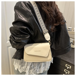 Chic cream canvas crossbody bag with wide shoulder strap worn by model in leather jacket