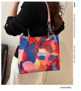 Detail of colorful printed tote bag featuring nylon patchwork and pink metal chain strap