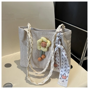 Macro detail of cream woven straw tote featuring textured chevron patterns and sunflower charm
