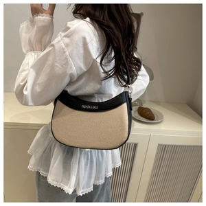 Détail du sac hobo en toile beige avec bordure noire et typographie de mode imprimée