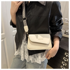 Detail of cream small crossbody bag featuring a wide jacquard strap and fashion lettering