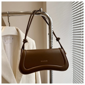 Detail of a brown leather underarm bag with gold logo and stylish knotted shoulder strap