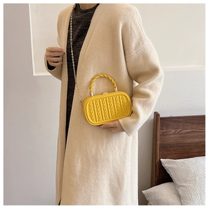 Detail view of yellow box bag featuring embossed rope texture and gold chain strap