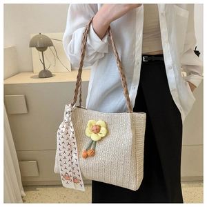 Detail of beige woven straw tote bag with yellow flower ornament and patterned silk scarf