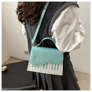 Detail of blue piano note crossbody bag with gold treble clef embroidery and keyboard print