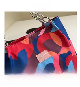 Close-up of multicolor geometric tote bag with silver chain strap and brand logo