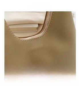 Macro shot of fine pebbled leather texture and silver zipper detail on the khaki handbag