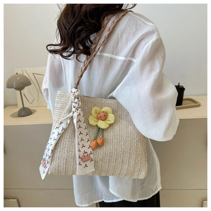 Detail of woven straw tote bag with braided rope strap, plush flower and printed silk scarf