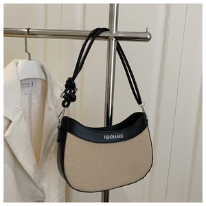 Détail du sac croissant en toile avec bordures en cuir noir et bandoulière à nœuds