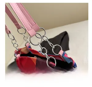 Detail of pink leather strap and silver metal ring chain on a patterned tote bag