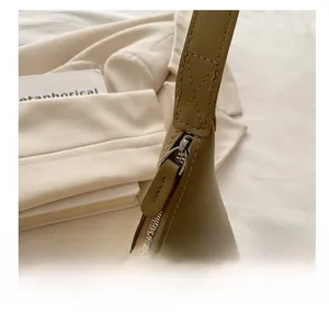 Close-up of smooth metal zipper and leather puller on a minimalist shoulder bag