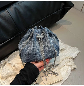 Detail of blue denim bucket bag with silver sequins, chain strap and pearl drawstring