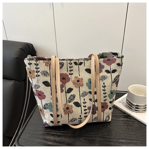 Detail of colorful floral woven tote bag with brown faux leather straps on a chair