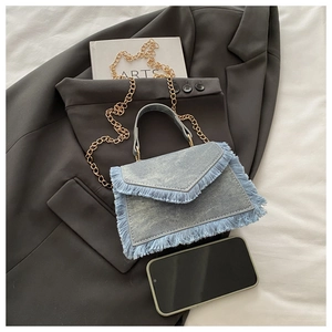 Dettaglio della borsa in denim con catena dorata e dettagli di frange alla moda