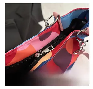 Top detail of colorful tote bag with geometric patterns, smooth zipper, and silver hardware