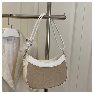 Détail du sac bandoulière en toile avec bordure en cuir, sangle nouée et texte imprimé