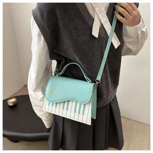 Detail of mint green music-themed crossbody bag with piano keys and treble clef