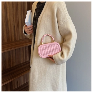 Detail of pink embossed woven texture bag with gold chain strap and twisted handle