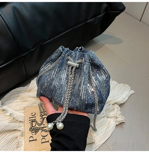 Detail of blue denim bucket bag featuring silver sequins and elegant pearl drawstring