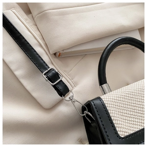 Détail d'un sac à main en tweed bicolore avec garniture en cuir noir et boucles