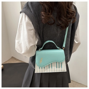 Detail of mint green piano crossbody bag with gold treble clef and keyboard pattern