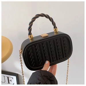 Macro detail of black embossed chain box bag featuring vertical cable texture and gold lock