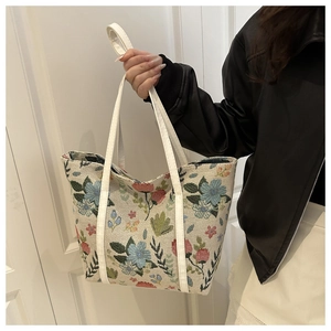 Close-up of floral embroidery on large canvas tote bag with white leather handles