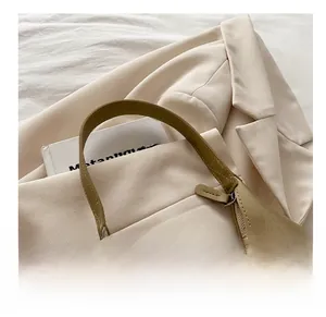 Detail of olive green hobo bag leather texture with metal zipper on beige suit jacket