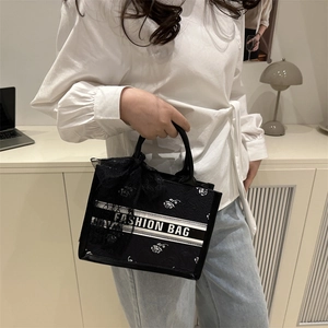 Elegant black tote bag with white rose embroidery and a chic black lace bow handle detail