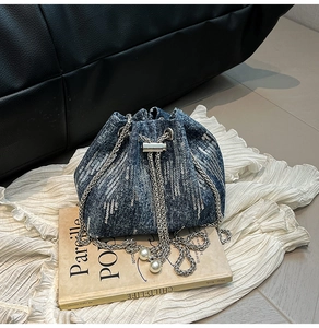 Close-up of sequins denim bucket bag with metal chain drawstrings and pearl charms