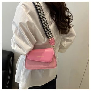 Detail of pink crossbody bag with wide geometric strap and gold hardware accents