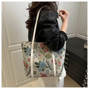 Detail of vintage floral jacquard tote bag with blue and pink flowers on model