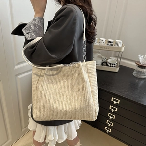 Large beige woven tote bag with herringbone pattern and metal chain leather straps
