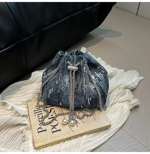 Close-up of sequin denim bucket bag with silver chain and white pearl drawstring details
