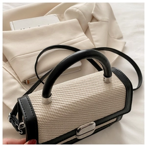 Gros plan sur la texture tissée et les finitions en cuir noir d'un sac bandoulière chic