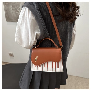 Detail of piano key pattern and golden treble clef charm on a stylish crossbody bag