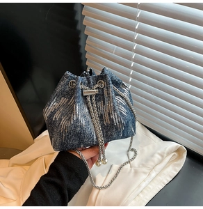 Detail of denim bucket bag with silver sequins, chain strap and pearl drawstring