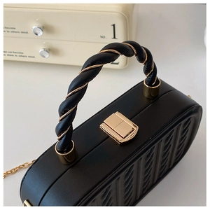 Detailed close-up of a black quilted handbag featuring a unique twisted golden handle