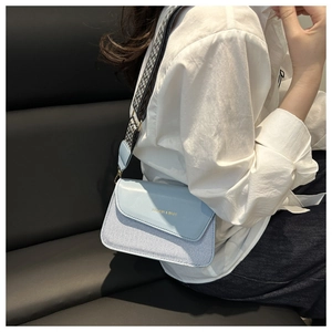 Detail of light blue crossbody bag with gold fashion text and geometric wide strap